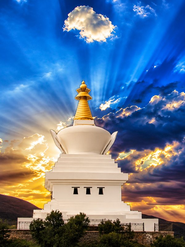 White stupa against a sky full of light rays